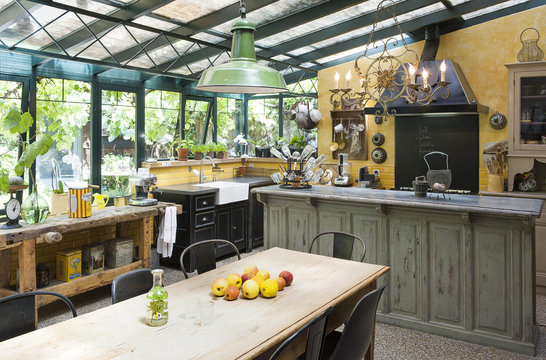 Cuisine install&eacute;e dans un jardin d'hiver d'une ancienne maison et son mobilier chin&eacute; trouv&eacute; en brocante pour un style vintage