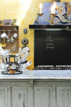 Cuisine ambiance brocante dans une ancienne maison avec plan de travail en bois et zinc et tableau noir pour noter la liste &agrave; commissions