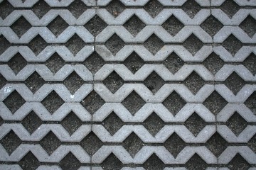 Narrow rectangular gray tiles laid out in the form of intertwining lines - a lattice or honeycomb pattern