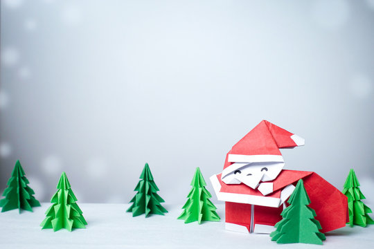 Santa claus in snowy winter background with paper cut christmas tree