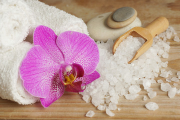 Spa set with white towels, sea salt, wooden spatula and bright orchid flower