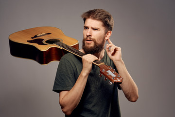 A man with a beard on a gray background holds a guitar, musician, music