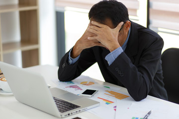 The man are stressed at work in the office. Asian businessman stressful and headache with laptop computer. Young male with headache at office, feeling sick at work.