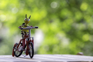 Bee dolls riding a bicycle on wooden ,background bokeh
