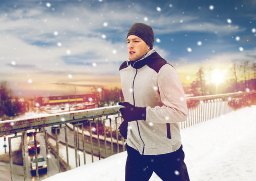 man in earphones running along winter bridge