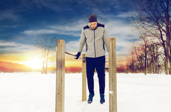 young man exercising on parallel bars in winter