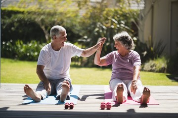 Cheerful senior couple giving high five while exercising