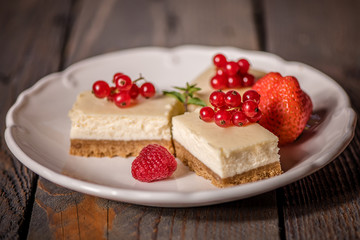 cheescake on a white plate decorated with fruit and red berries