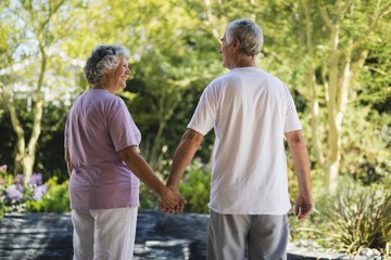 Rear view of happy senior couple holding hands while standing at