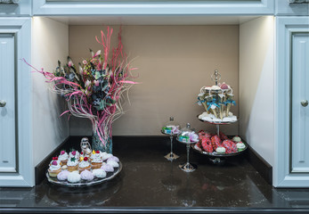 Fragment of the kitchen in a classic style. Table top made of black marble. Many different sweet dishes in beautiful vases