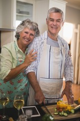 Portrait of smiling senior couple preparing food in kitchen