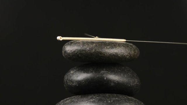 Akupunkturnadel auf einem schwarzen Stein auf 
einem Drehteller
