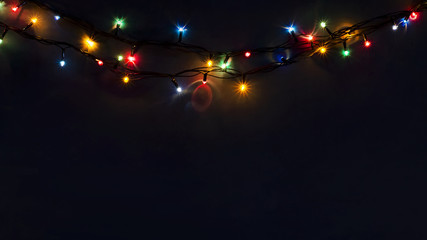 Glowing New Year garlands on a dark background. Copy space. Christmas, New Year background.