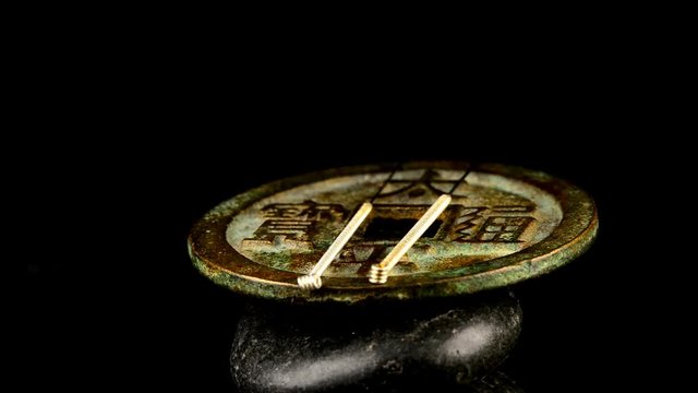 Akupunkturnadeln auf antiker chinesischer Münze 

auf einem Drehteller
