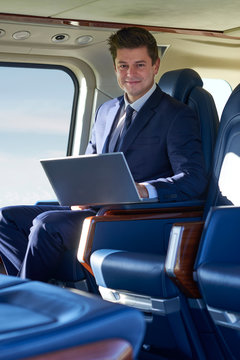 Portrait Of Businessman Working On Laptop In Helicopter Cabin During Flight