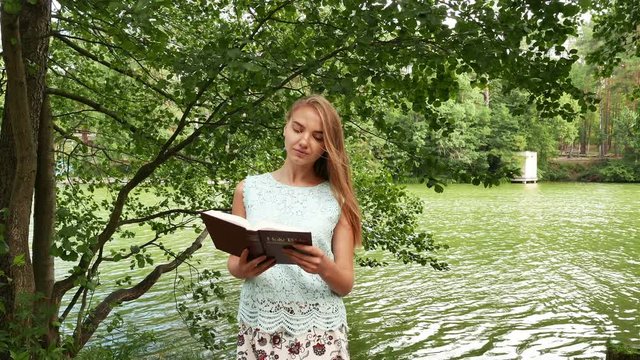 4k. Christian Bible  and attractive young girl in park