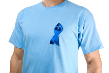 Young man in t-shirt with symbolic blue ribbon on white background. Cancer awareness concept