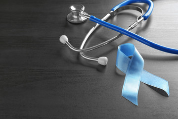 Blue ribbon and stethoscope on wooden background. Cancer awareness concept