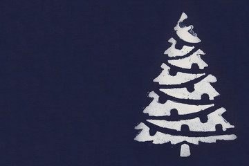 One white Christmas tree painted with paint through a stencil on a dark blue background. Copy space.