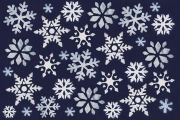 Fototapeta na wymiar A lot of white snowflake painted with paint through a stencil on a dark blue background.