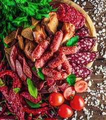 Food tray with delicious salami, pieces of sliced ham, sausage, tomatoes, salad and vegetable.