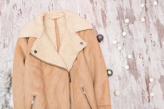 Beige sheepskin coat on a wooden background. Fashionable concept