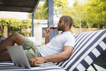 Man drinking red wine while relaxing at porch