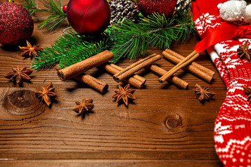 Christmas red sock and the branches green spruce with cones and toys and cinnamon sticks and star anise on a wooden background
