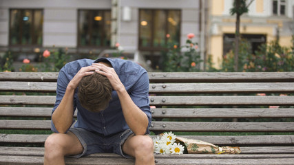 Desperate young man sitting alone on bench, suffering depression after break-up