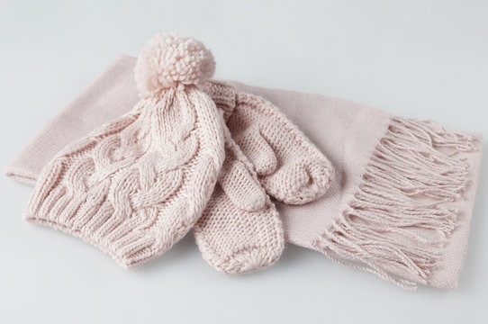 Pale pink gloves, scarf and woolen hat woman winter set on white background