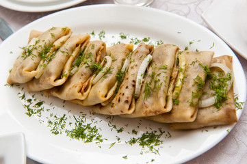 Pancakes with meat sprinkled with herbs and pickled onions