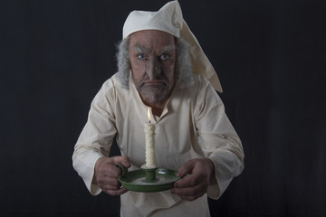 Mature man in old fashioned Victorian night shirt holding a candle 