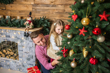 Christmas Eve, Dad and daughter decorate the Christmas tree at home.