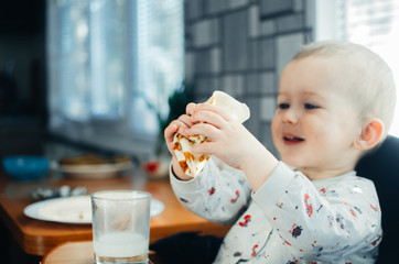 Young smiling little boy eating a pancake