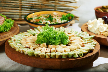 Shot of a big wooden plate with pancake rolls with creamy filling decorated with greens served on a party table at the restaurant festive gathering lifestyle eating food delicious.