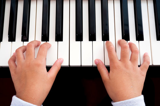 Girl playing piano. Closeup hands, top view. Art and music background. Concept of practice and education basic of music.