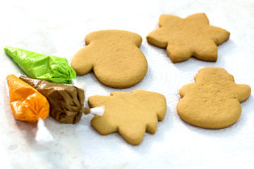 Four Christmas gingerbread and piping bags with a glaze of green, brown and orange. Handmade cookies in the form of a mitten, a Christmas tree, a snowman and a snowflake.