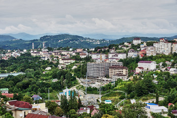 Obraz premium Panorama of the city of Sochi from a bird's eye view/Panorama of Sochi from the air. Houses, streets, trees, the sky are visible. In the distance you can see the sea. Sochi, Russia, cityscape