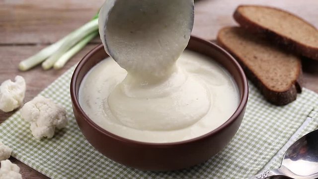 cream soup is poured into a plate. under a plate a napkin in a green box. next to it there is salt, pepper is scattered, bread and garlic lie on the table