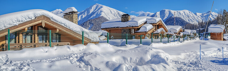 RED GLADE, SOCHI, RUSSIA - JANUARY 31, 2016: Snow-covered cottages against the backdrop of the mountains. Mountain resort "Laura, GAZPROM". Near Sochi, Russia on January 31, 2016.