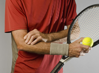 male tennis player massaging painful elbow holding racket