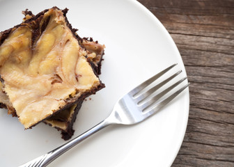 Cheese brownies on white plate. Homemade dessert for chocolate lover. Served on wooden table.