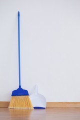 Dustpan and sweeping broom leaning against white wall