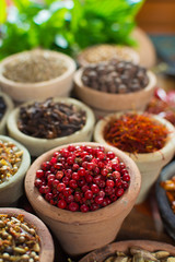 Variety of different spices with focus on pink Peruvian pepper, false pepper used in four peppers blends
