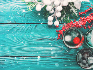 Christmas party green alcohol drinks with cherry. Festive aperitif shots and ornaments on wooden...