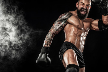 Fototapeta na wymiar Sportsman muay thai boxer fighting on black background with smoke. Copy Space. Sport concept.