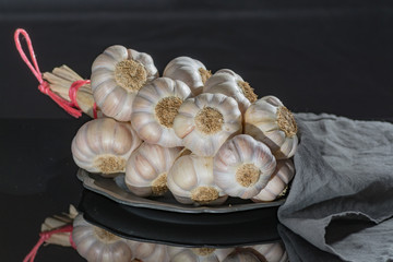 String of french pink garlic on old tin plate on black background