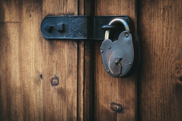 Old metal padlock on vintage wooden door