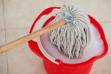 Bucket with foamy water and mopping the tile floor © WavebreakMediaMicro