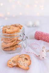 Fototapeta na wymiar Almond cookies packaged in a glass jar. Candles and christmas lights in the background.